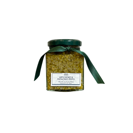 Jar of artichoke pesto with a green ribbon on a white background